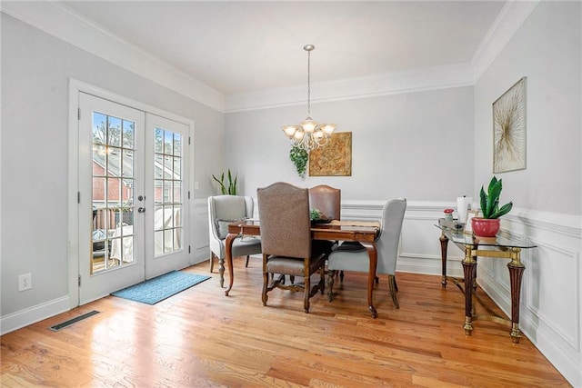 dining space with ornamental molding, light hardwood / wood-style flooring, french doors, and a notable chandelier