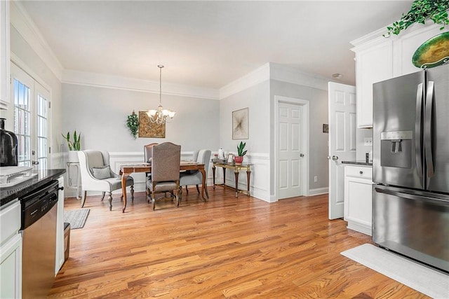 kitchen with light hardwood / wood-style flooring, a notable chandelier, decorative light fixtures, white cabinets, and appliances with stainless steel finishes