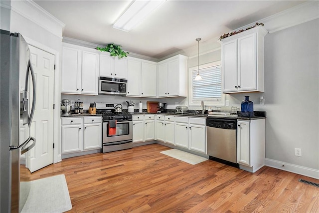 kitchen featuring white cabinetry, stainless steel appliances, hanging light fixtures, and light hardwood / wood-style flooring