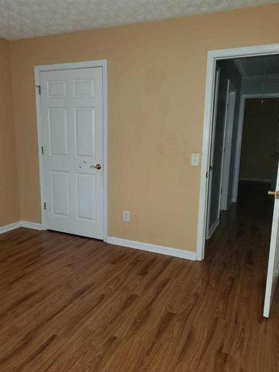 unfurnished room featuring dark hardwood / wood-style flooring and a textured ceiling