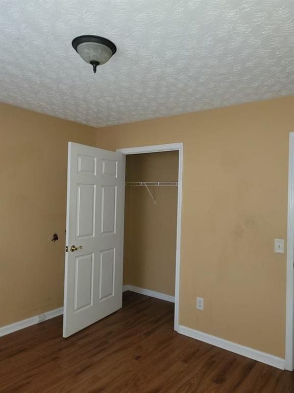 unfurnished bedroom featuring dark hardwood / wood-style flooring, a closet, and a textured ceiling