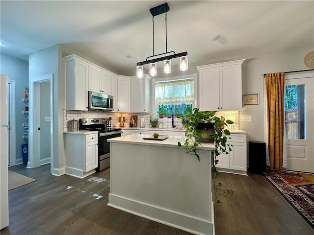 kitchen with dark wood-type flooring, decorative backsplash, appliances with stainless steel finishes, decorative light fixtures, and white cabinetry