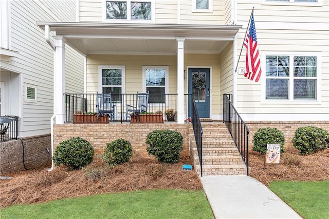 property entrance featuring covered porch and brick siding