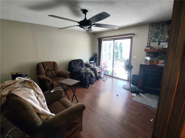 living room with wood-type flooring, ceiling fan, a textured ceiling, and a fireplace