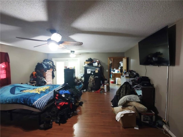 bedroom with hardwood / wood-style flooring, ceiling fan, and a textured ceiling