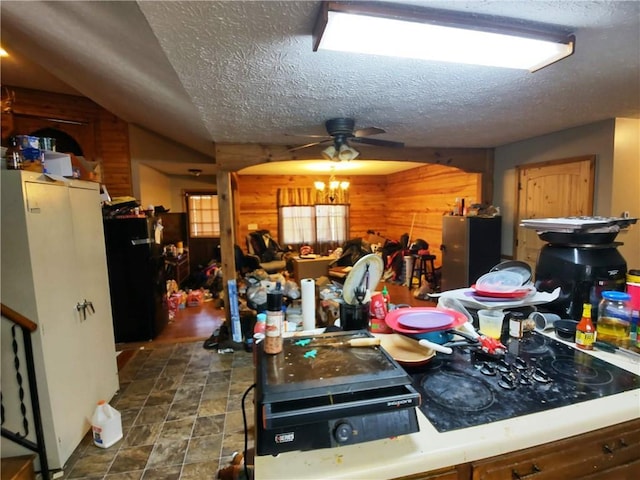 kitchen featuring black fridge, ceiling fan, a textured ceiling, and wood walls