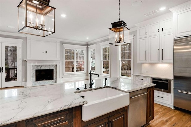 kitchen with sink, hanging light fixtures, stainless steel appliances, ornamental molding, and white cabinets