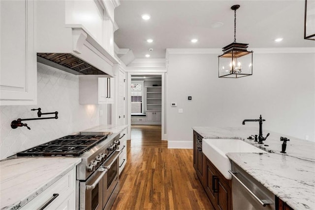 kitchen featuring premium range hood, white cabinetry, light stone counters, stainless steel appliances, and decorative backsplash