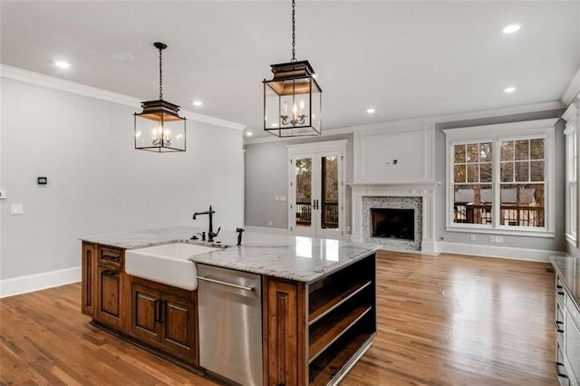 kitchen with ornamental molding, stainless steel dishwasher, a center island with sink, and light wood-type flooring