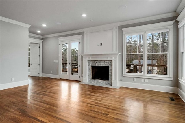 unfurnished living room featuring crown molding, a wealth of natural light, french doors, and wood-type flooring