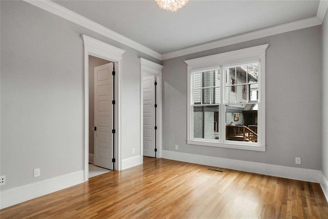 unfurnished room with crown molding, an inviting chandelier, and hardwood / wood-style flooring