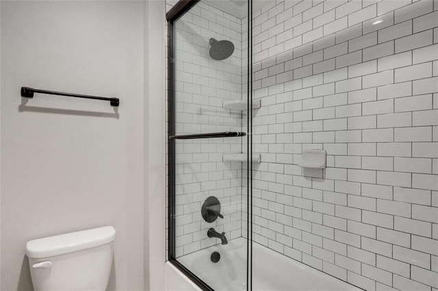 bathroom featuring bath / shower combo with glass door and toilet