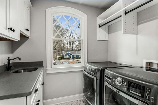 laundry area featuring sink, washing machine and dryer, and cabinets