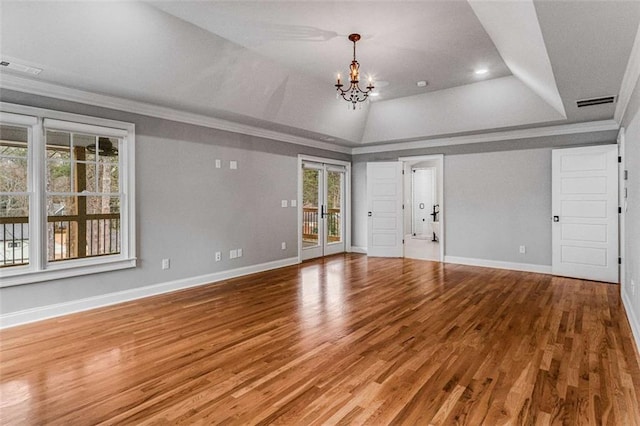 unfurnished living room with hardwood / wood-style floors, a tray ceiling, ornamental molding, and a notable chandelier