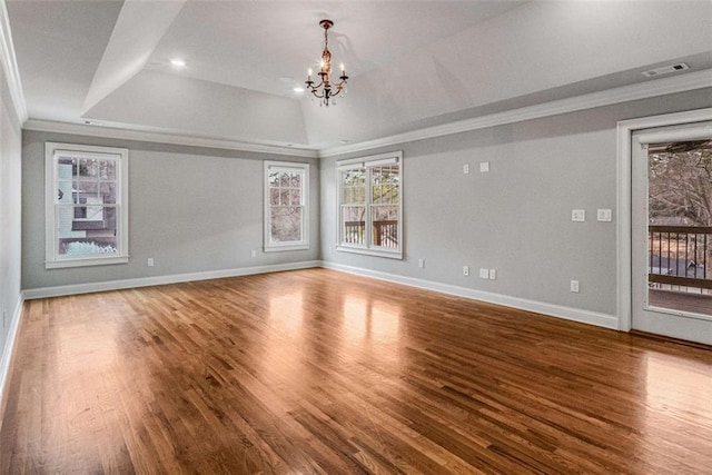 spare room featuring hardwood / wood-style flooring, ornamental molding, a tray ceiling, and a notable chandelier