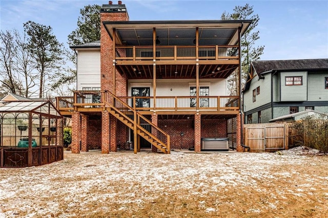 rear view of house featuring a wooden deck and a hot tub