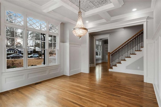 unfurnished dining area featuring coffered ceiling, wood-type flooring, and ornamental molding