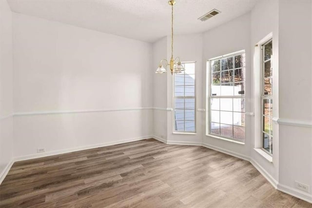 unfurnished dining area with wood-type flooring and a chandelier