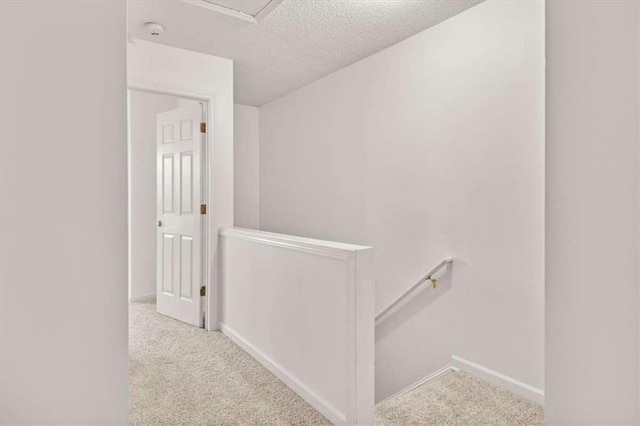 hallway featuring light carpet and a textured ceiling