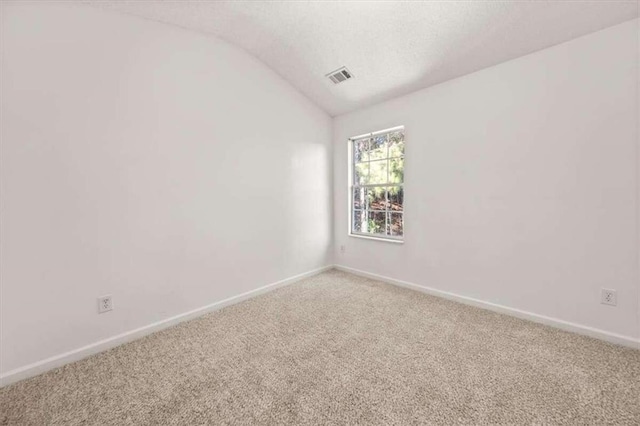 empty room featuring vaulted ceiling and carpet flooring