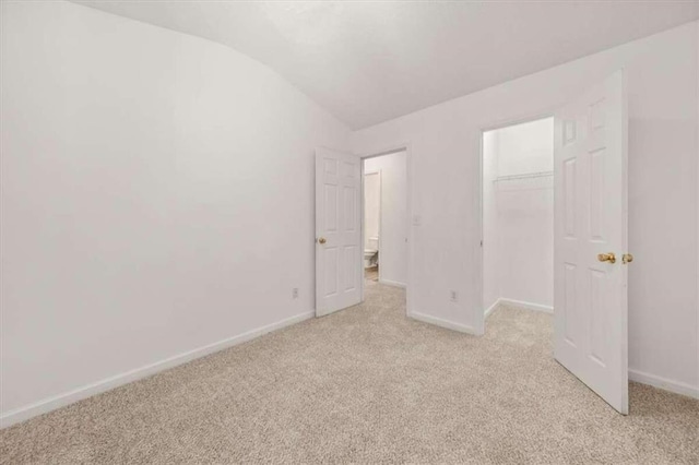 unfurnished bedroom with lofted ceiling, light colored carpet, and a closet