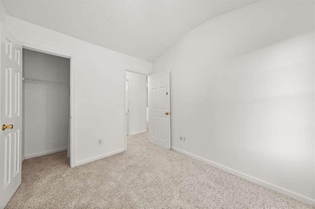 unfurnished bedroom with light carpet, vaulted ceiling, and a closet