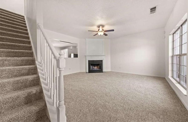 unfurnished living room with ceiling fan and carpet