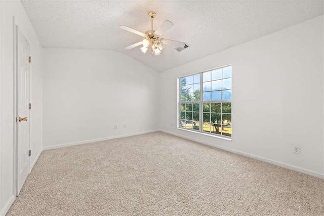 spare room featuring light colored carpet, vaulted ceiling, a textured ceiling, and ceiling fan