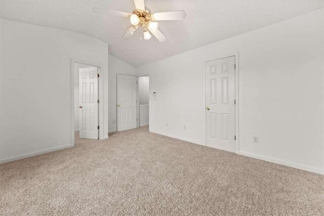 unfurnished bedroom featuring lofted ceiling, light colored carpet, and ceiling fan