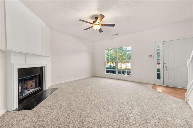 unfurnished living room with ceiling fan, hardwood / wood-style flooring, and a textured ceiling