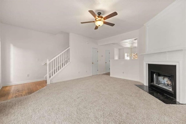 unfurnished living room with ceiling fan with notable chandelier and wood-type flooring