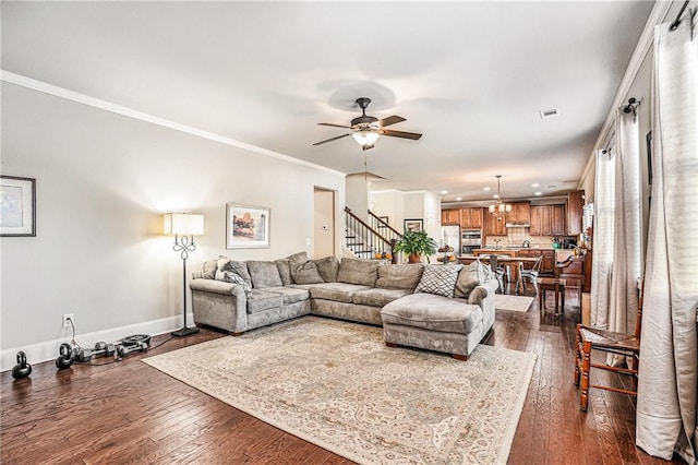 living room with ornamental molding, dark hardwood / wood-style floors, and ceiling fan with notable chandelier