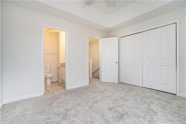 unfurnished bedroom with light carpet, ensuite bath, a closet, and ceiling fan