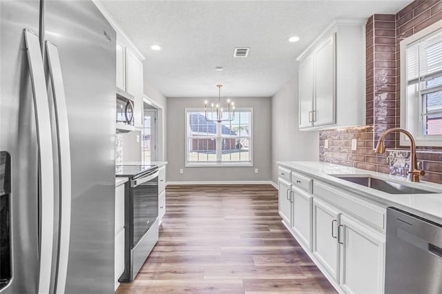 kitchen with sink, tasteful backsplash, light hardwood / wood-style flooring, appliances with stainless steel finishes, and white cabinets