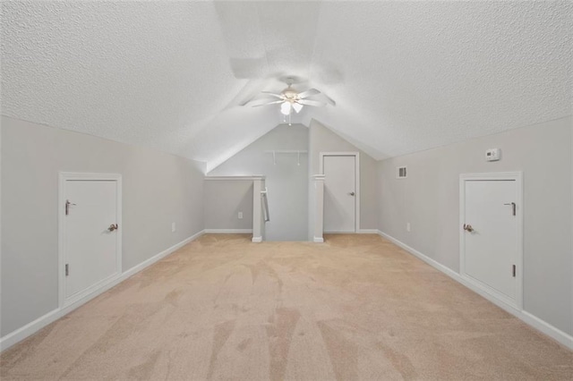 additional living space with ceiling fan, lofted ceiling, light carpet, and a textured ceiling