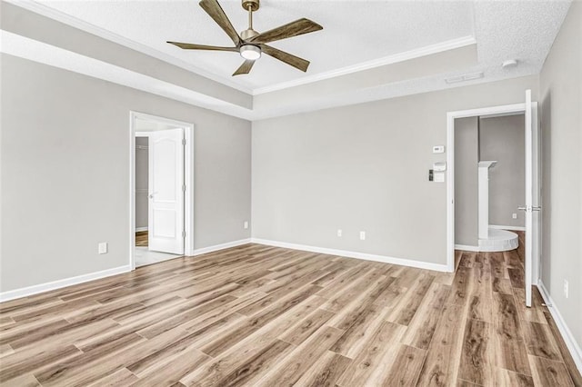 unfurnished room featuring a tray ceiling, light hardwood / wood-style floors, ceiling fan, and a textured ceiling