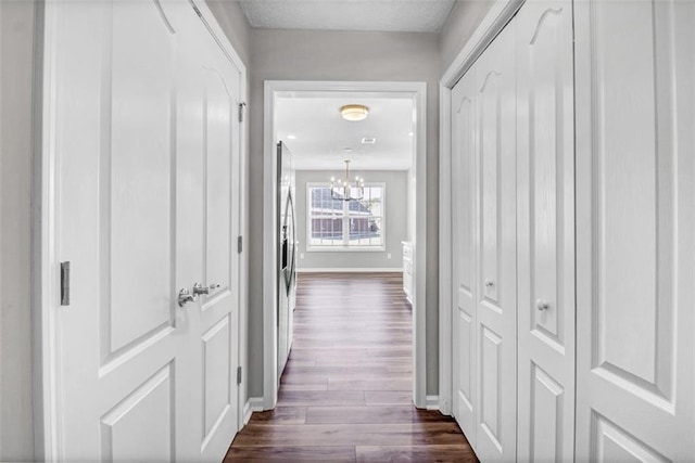 hallway with dark hardwood / wood-style floors and a chandelier