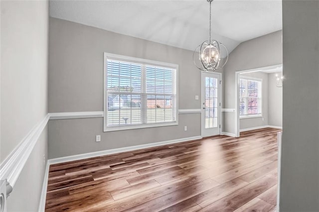 entryway featuring an inviting chandelier, a wealth of natural light, and hardwood / wood-style flooring