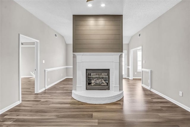 unfurnished living room with a textured ceiling, vaulted ceiling, and wood-type flooring