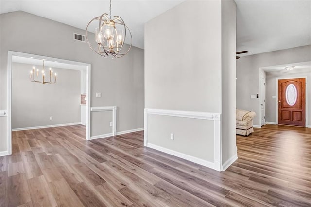 interior space featuring vaulted ceiling, ceiling fan with notable chandelier, and hardwood / wood-style floors