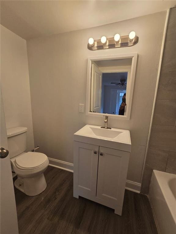 bathroom featuring vanity, hardwood / wood-style flooring, toilet, and a tub