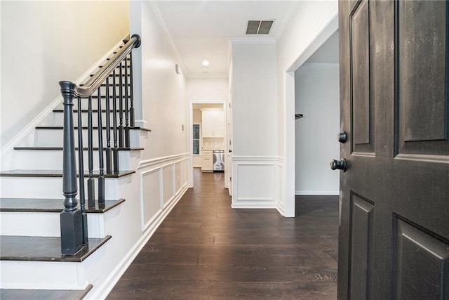 interior space featuring visible vents, ornamental molding, wood finished floors, wainscoting, and a decorative wall