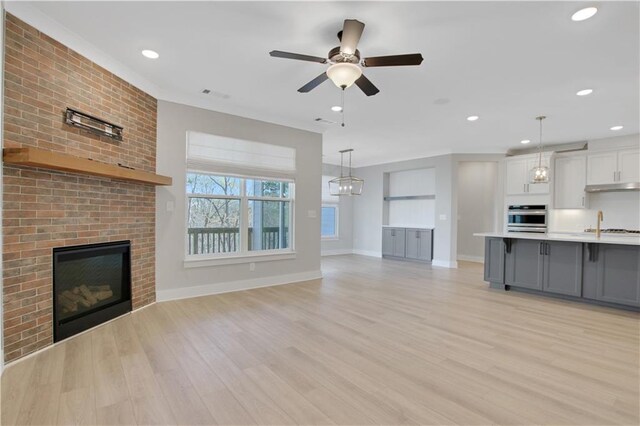 kitchen with sink, gray cabinetry, appliances with stainless steel finishes, pendant lighting, and a kitchen island with sink