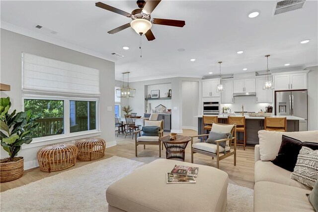 living room featuring crown molding, ceiling fan, and a brick fireplace