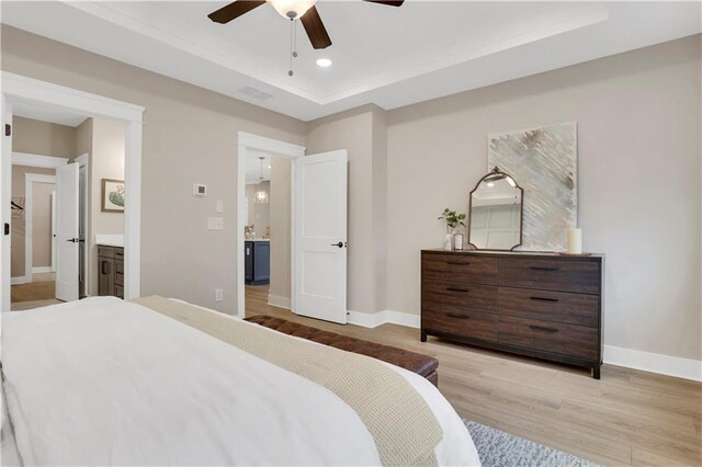 bedroom with multiple windows, ceiling fan, light hardwood / wood-style floors, and a tray ceiling