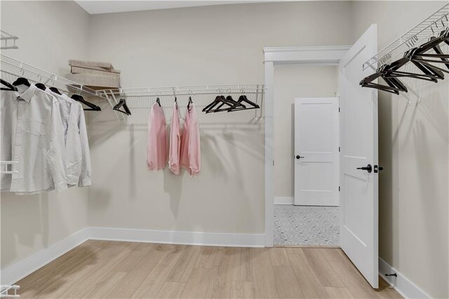 bedroom with ceiling fan, ensuite bathroom, a tray ceiling, and light wood-type flooring