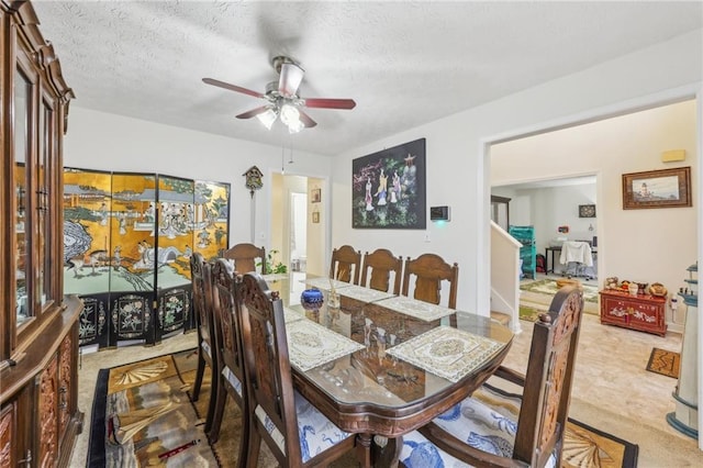 dining room featuring carpet flooring, ceiling fan, and a textured ceiling