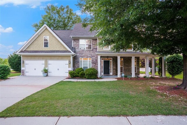 view of front of home with a garage, covered porch, and a front yard