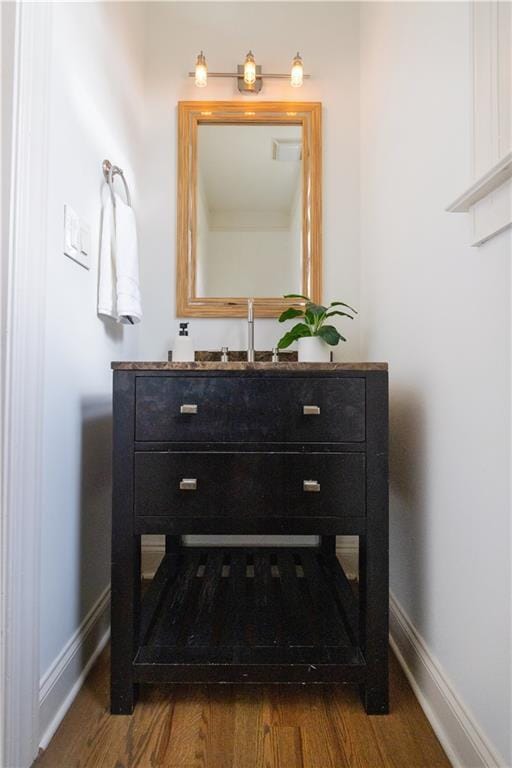 bathroom with vanity, wood finished floors, and baseboards