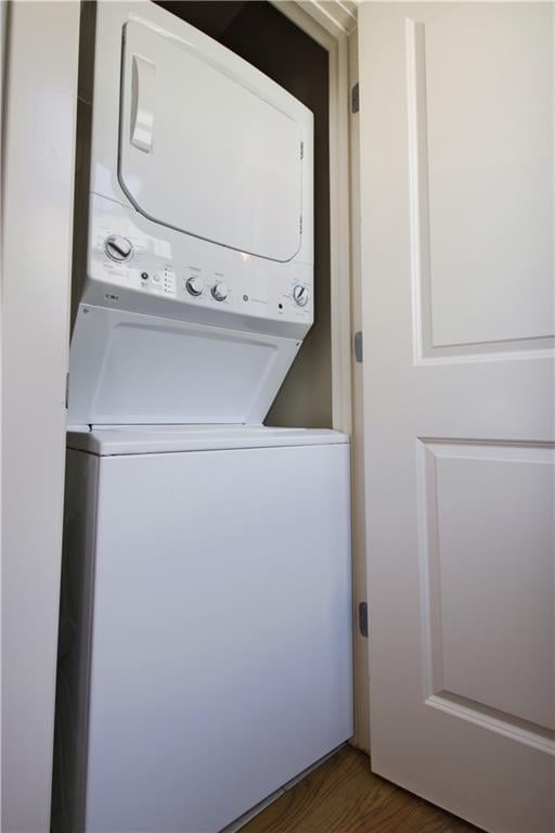 laundry room with dark wood-style flooring, laundry area, and stacked washer / dryer